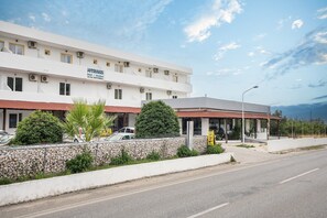 Un hôtel à la façade blanche, doté de nombreuses fenêtres et d’un mur en pierre orné de verdure.