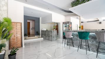 A modern kitchen with a marble countertop, a bar area with stools, and a wooden door.