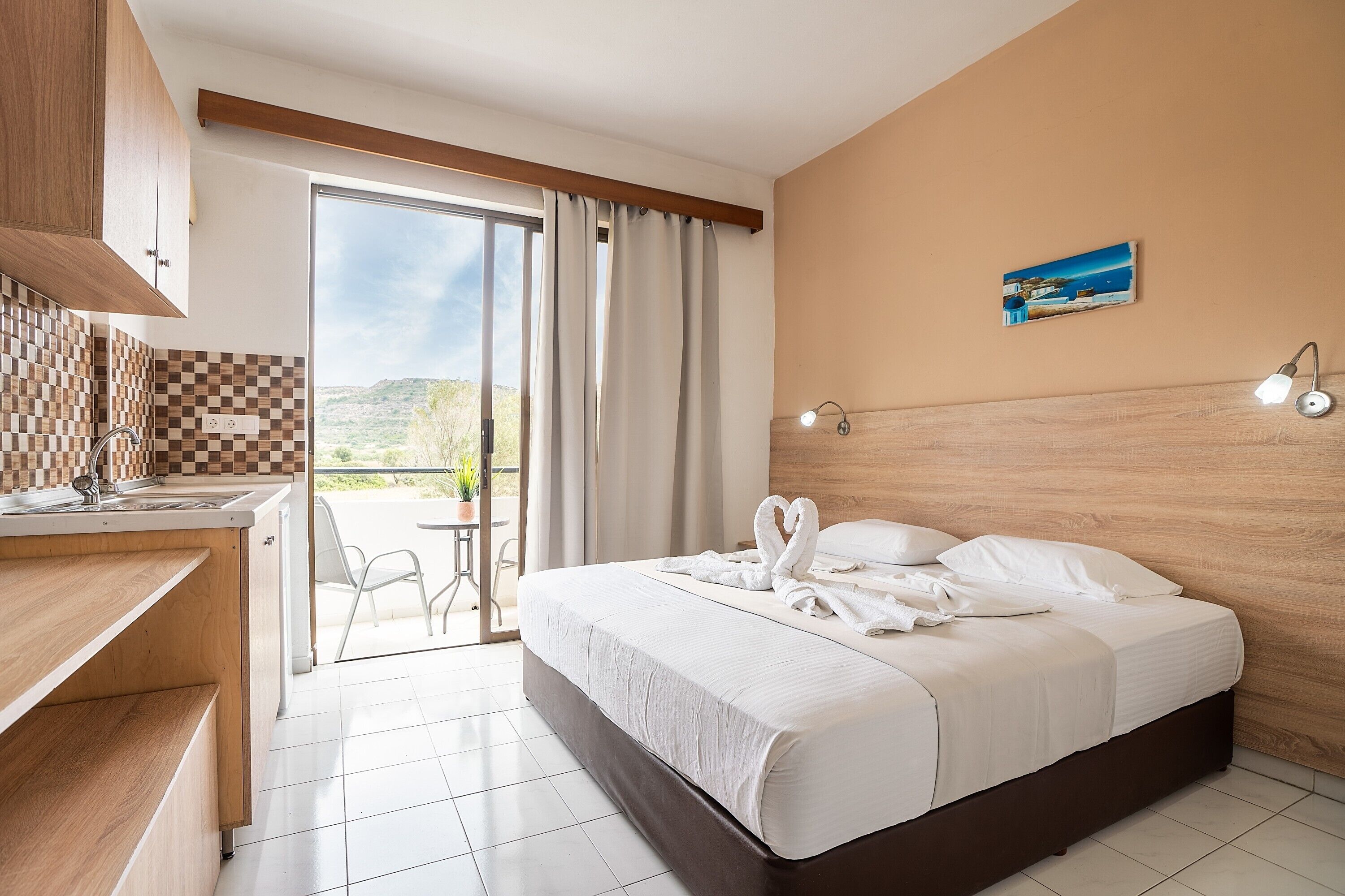 Una camera d'albergo con un letto, una scrivania, vista sull'esterno e un quadro appeso al muro.