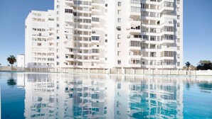 Ein Hochhaus mit mehreren Balkonen und einem klaren, blauen Pool davor.
