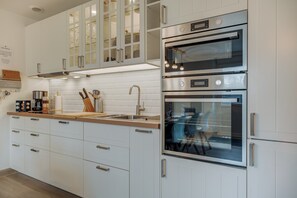 Une cuisine moderne avec des meubles blancs, des appareils en acier inoxydable et un four encastré.
