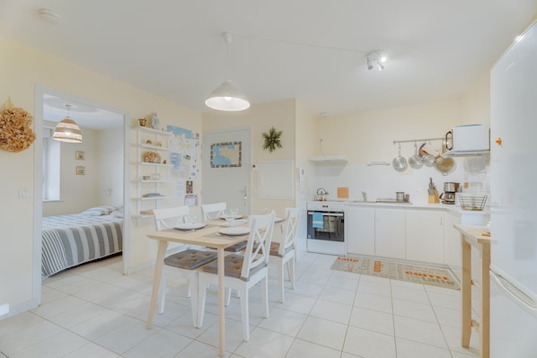 A compact living space with a dining area, kitchenette, and a bed.