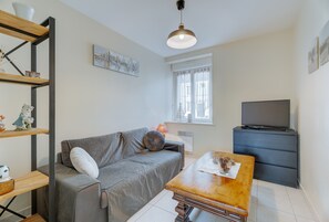 A living room with a sofa, a coffee table, a TV, and a bookshelf.