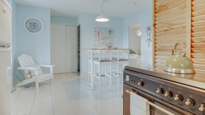 Una cocina con estufa, sillas y un reloj en la pared.