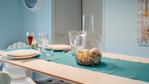 Una mesa de comedor con platos, vasos y una jarrón con conchas.