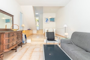 A living room with a sofa, a coffee table, a dresser, and a chair. There is a staircase leading to another room.