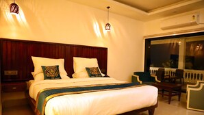 A hotel room with a large bed, two tiger-themed pillows, a wooden headboard, a patterned throw, and a view of the outside balcony.