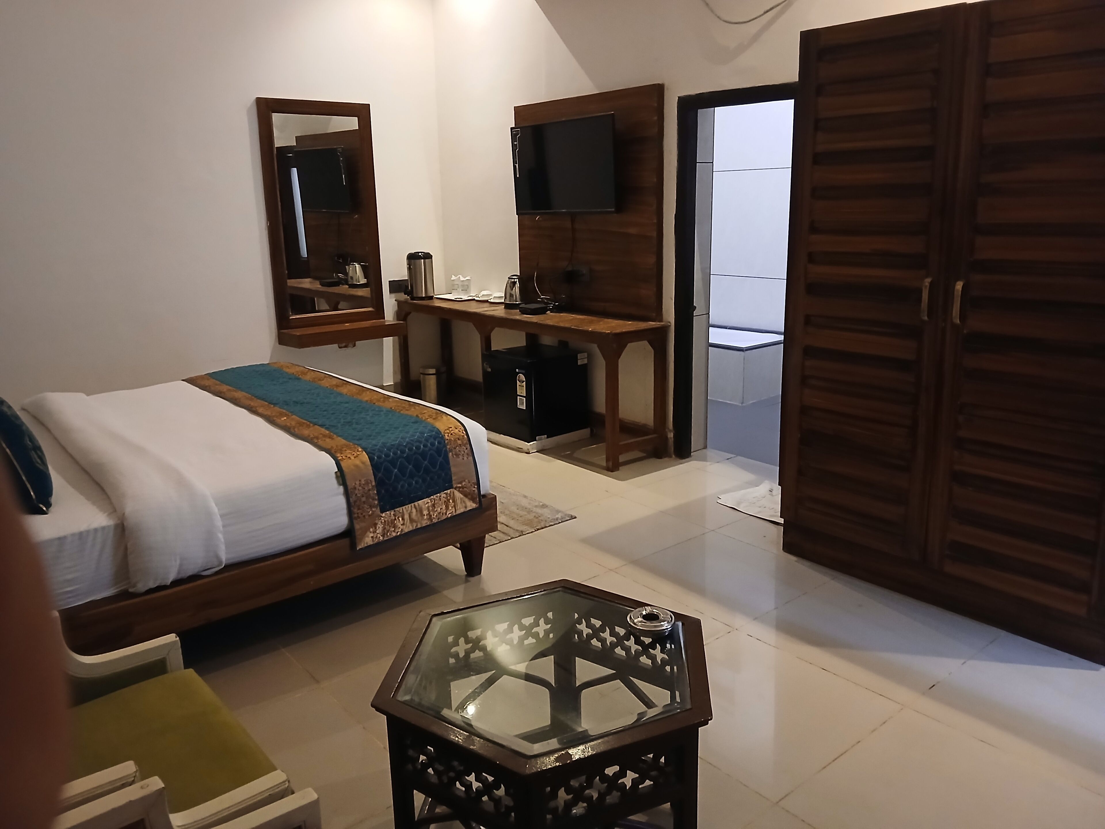 A hotel room with a bed, a desk, a TV, and a wardrobe.