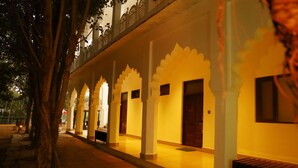 A corridor with white pillars and doors, leading to rooms.