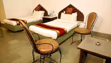 A hotel room with two single beds, a wooden chair, a small table, and a nightstand with a lamp.