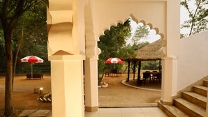 An outdoor area with a covered seating area, a thatched-roof structure, and a staircase leading up.