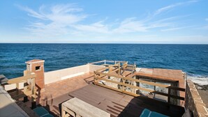 A wooden deck with a view of the ocean, a small brick structure, and a wooden railing. - Holiday Home "Casa Tenerife Primera Linea" with Sea Views, 3 Private Terraces and Wi-Fi (tenerife)