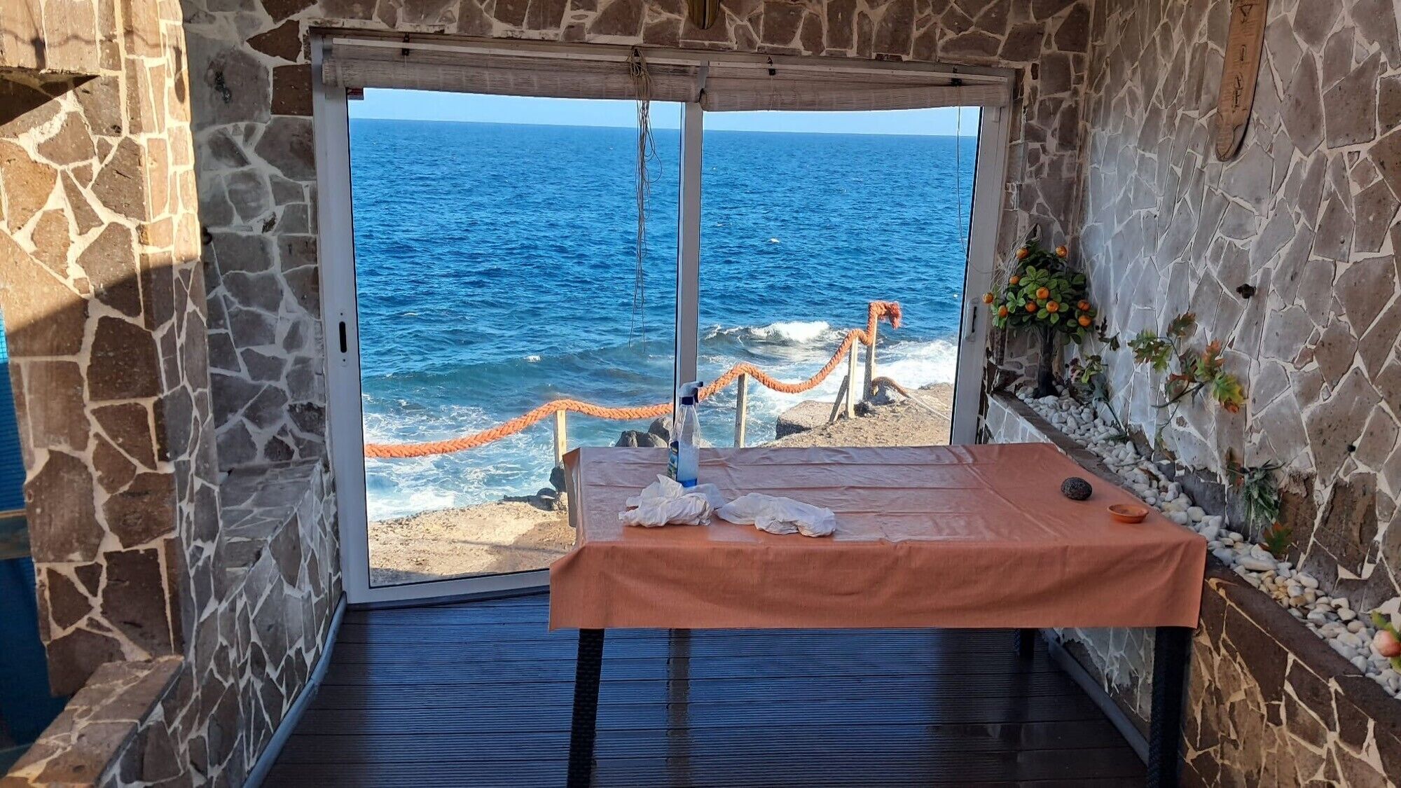 Ein Zimmer mit Steinwand, Meerblick und einer Massageliege.