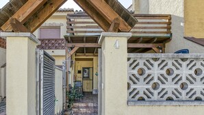 A narrow alleyway leading to a building with a number 4 sign, a gated entrance, and a decorative wall. - Vacation Home "Casa Empuriabrava Con Terraza" with 2 Private Terraces & Private Garden (Castelló d'Empúries)