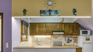 A kitchen with wooden cabinets, a marble countertop, a microwave, and a refrigerator. - Vacation Home "Casa Empuriabrava Con Terraza" with 2 Private Terraces & Private Garden (Castelló d'Empúries)