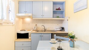 A compact kitchen with a microwave, toaster, sink, and a small dining table with a vase of flowers. - Studio Apartment 'Angelina 2' with Mountain View, Wi-Fi and Air Conditioning (Corfu)