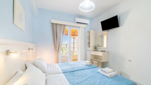 A bedroom with two beds, a TV, a bathroom, and a balcony. - Studio Apartment 'Angelina 2' with Mountain View, Wi-Fi and Air Conditioning (Corfu)