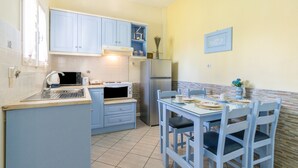 Una cocina compacta con armarios azules, un microondas, un refrigerador y una mesa de comedor con sillas.