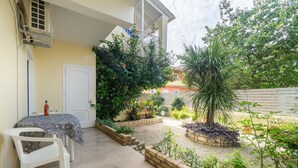 Un patio con una mesa, sillas, una puerta y varias plantas.