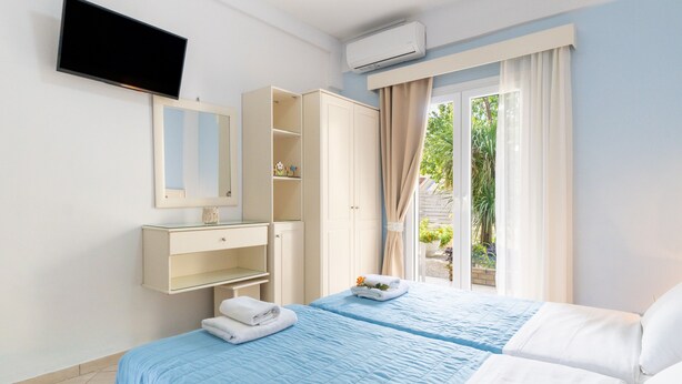 Una habitación de hotel con cama, televisión, armario y ventana con cortinas.