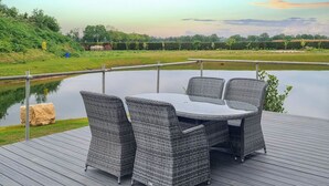 A deck with a table and chairs overlooking a body of water. - Rabbit Lodge is designed to provide you with a luxurious and comfortable stay. (Thorney, Nr Lincoln)