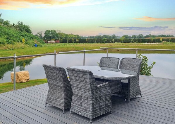 A deck with a table and chairs overlooking a body of water. - Rabbit Lodge is designed to provide you with a luxurious and comfortable stay. (Thorney, Nr Lincoln)