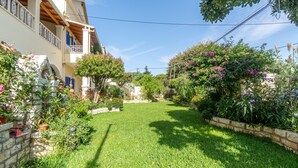 Un jardín bien cuidado con césped, muros de piedra y plantas en flor.