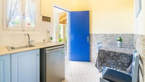 A compact kitchen with a sink, dishwasher, and a blue door leading to an outdoor area.