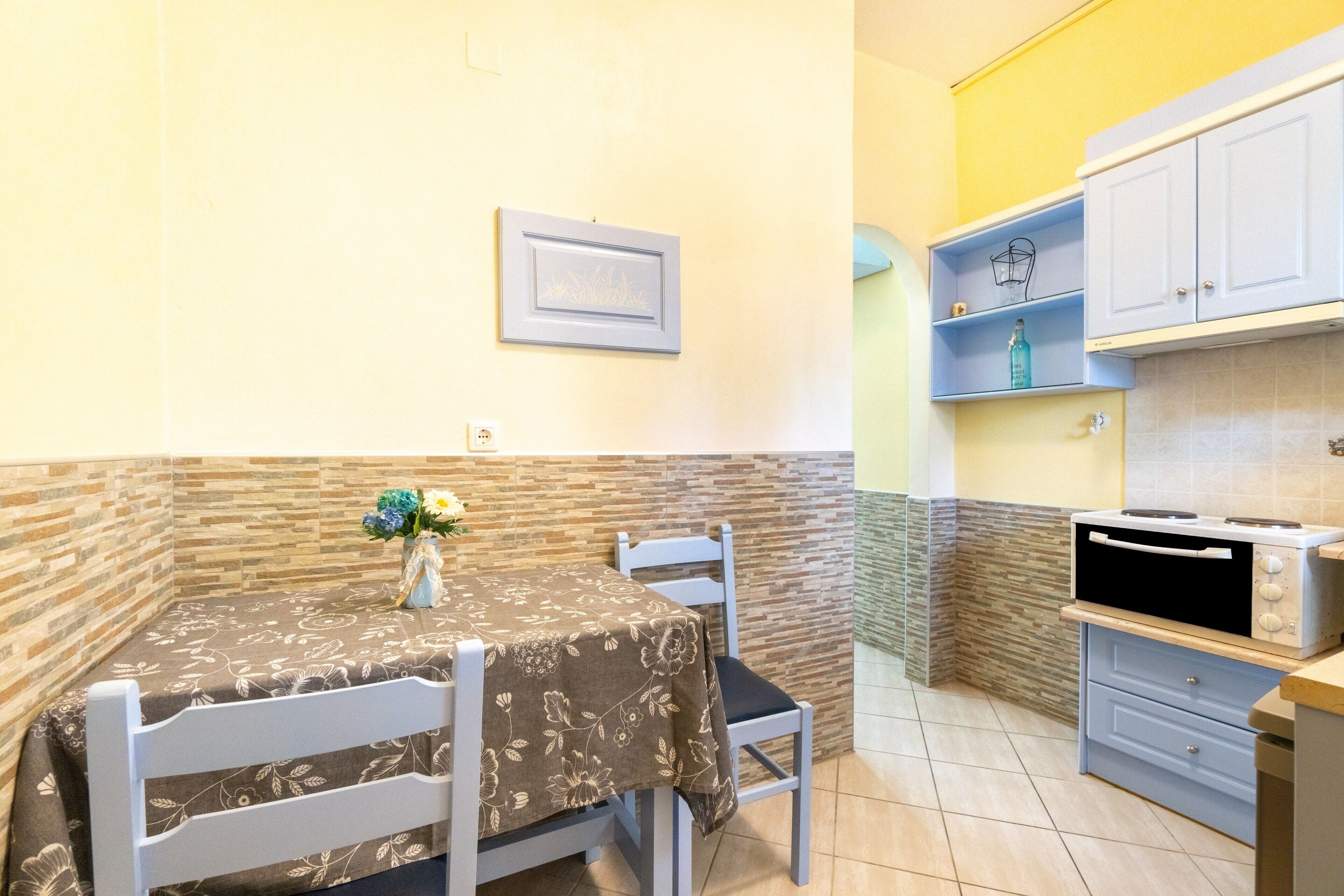 Una pequeña cocina con una mesa de comedor, sillas, un microondas y un armario.