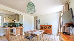 Una cocina moderna con comedor, armarios de madera y una lámpara colgante.