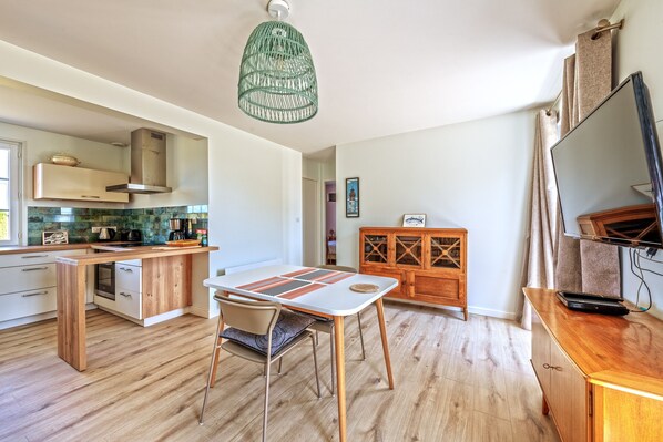 Une cuisine moderne avec un coin repas, des meubles en bois et un luminaire suspendu.