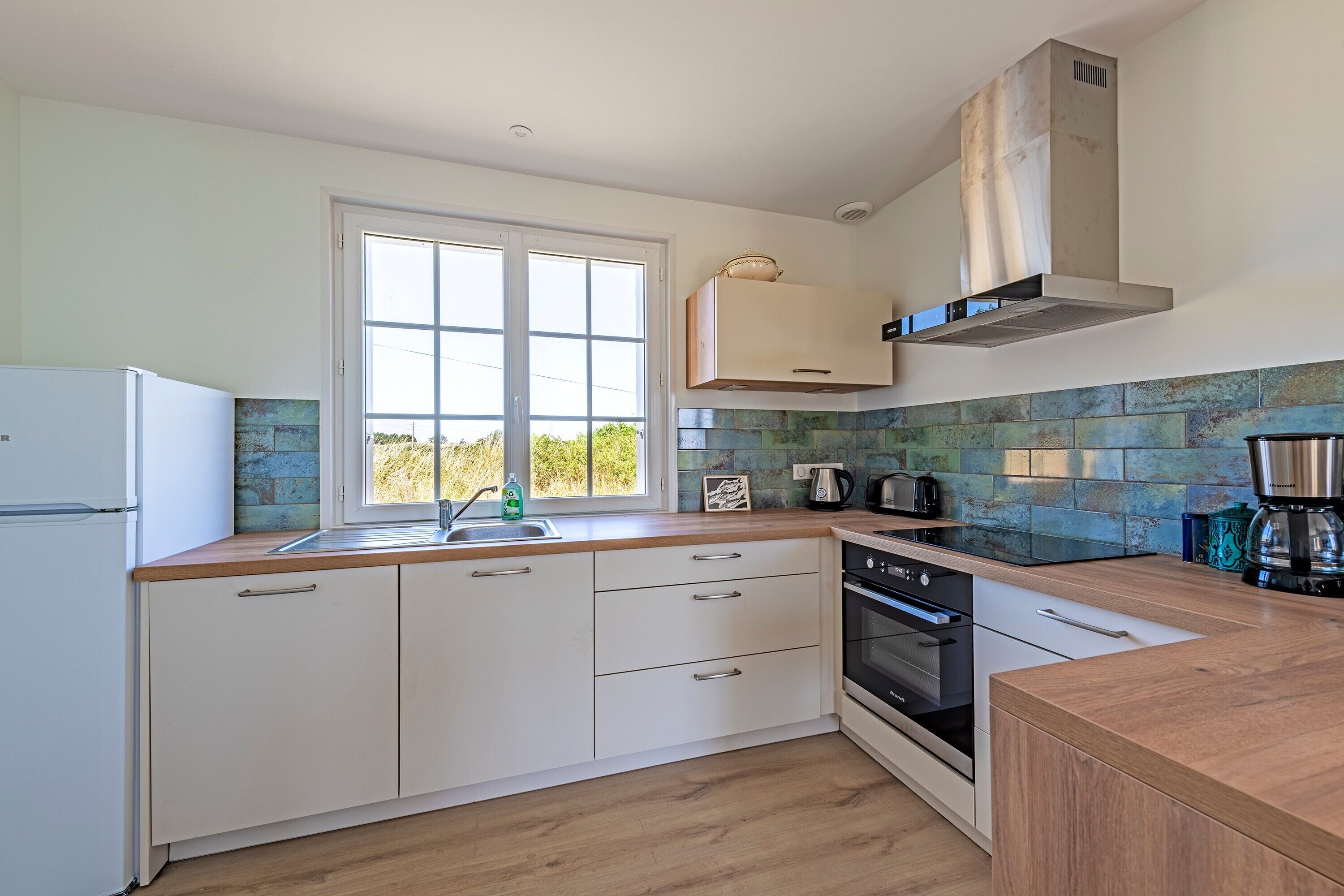 A kitchen with a window, white cabinets, a stove, and a dishwasher.