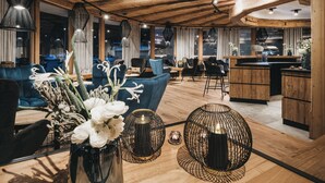 Un interior amplio y luminoso con techos de madera y muebles modernos, que incluye una zona de bar y diferentes disposiciones de asientos.