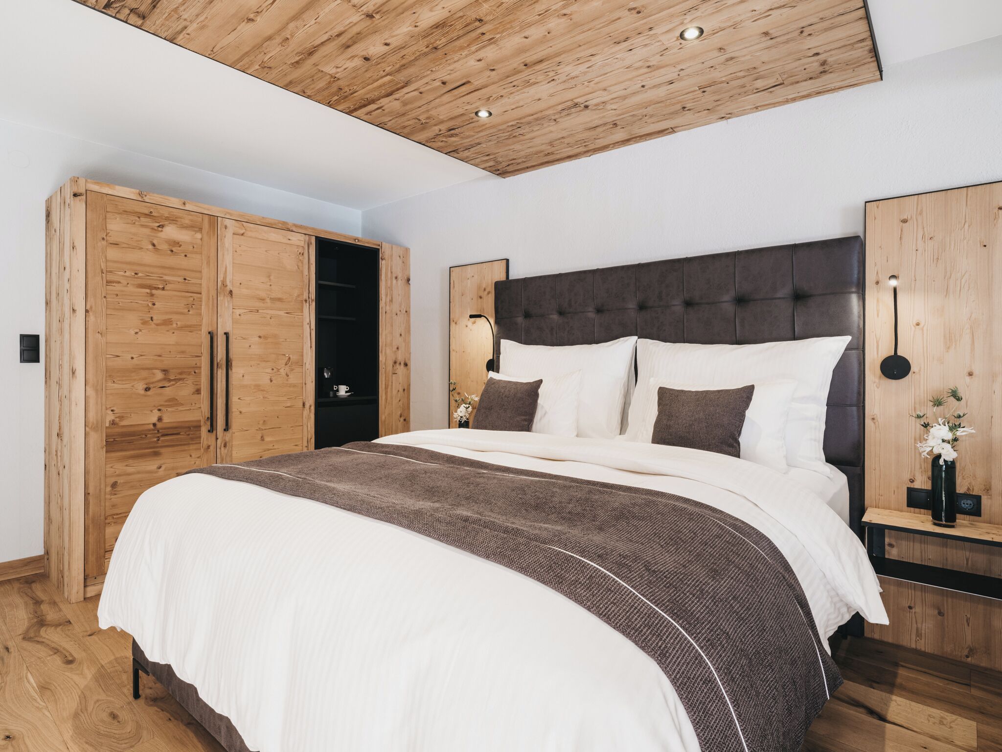 Una camera da letto con un letto grande, un'armadio in legno e un soffitto a vista con travi.
