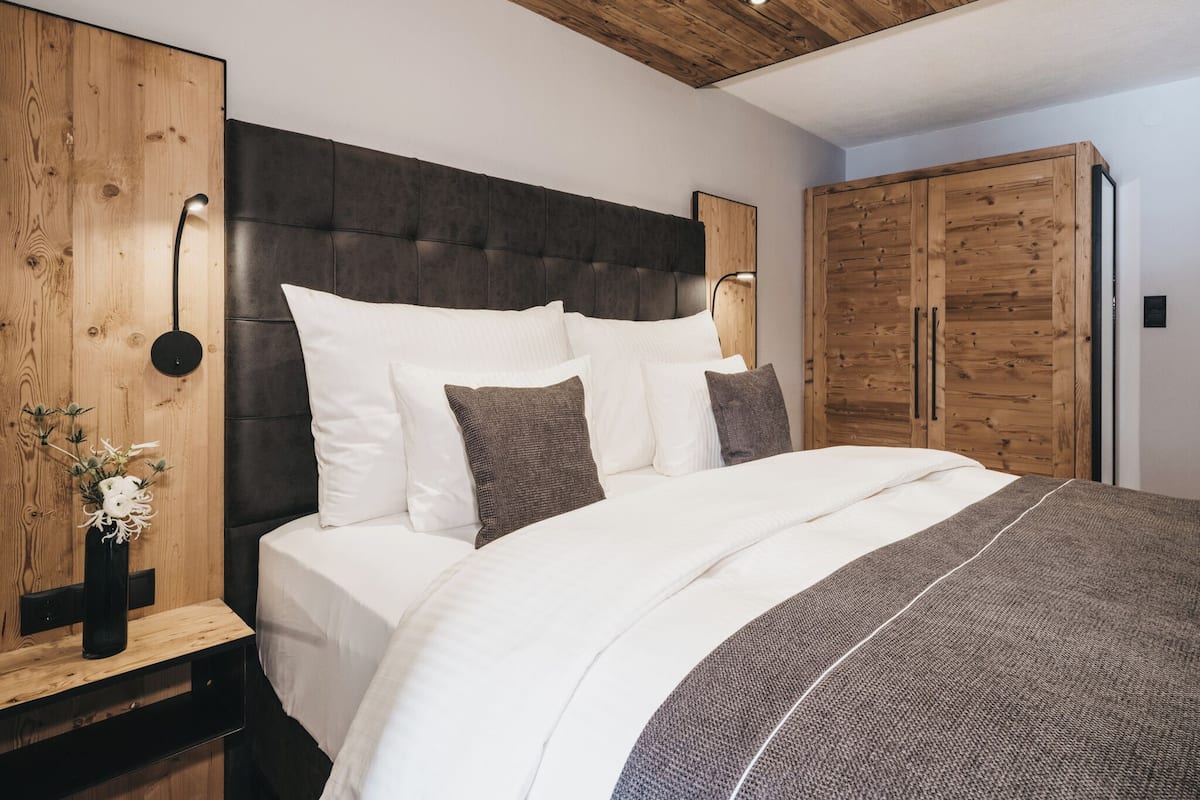 Un dormitorio moderno con una cama grande, cabecero de madera y un armario.