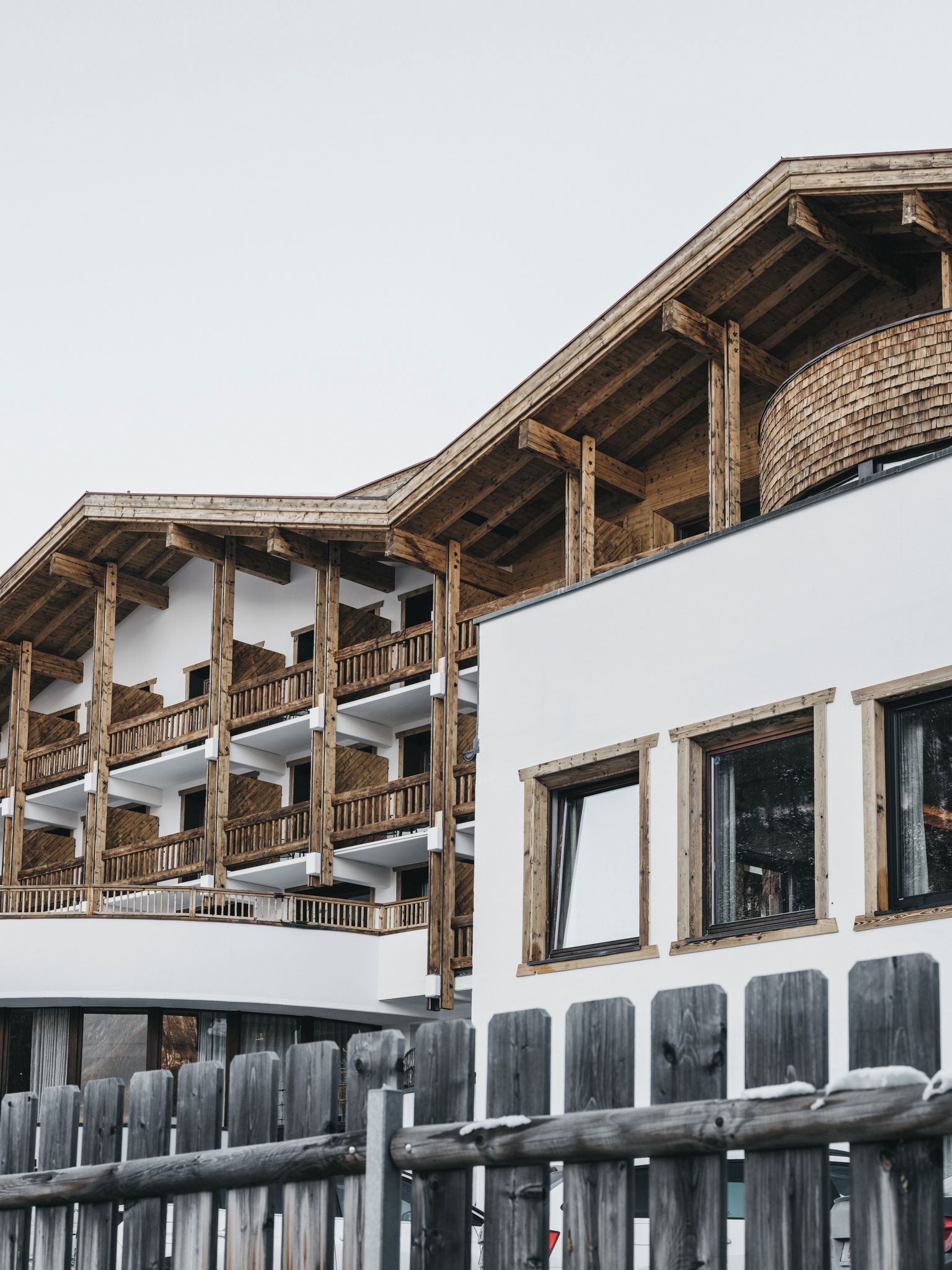 Un immeuble à plusieurs étages, doté de balcons en bois et d’une façade blanche.