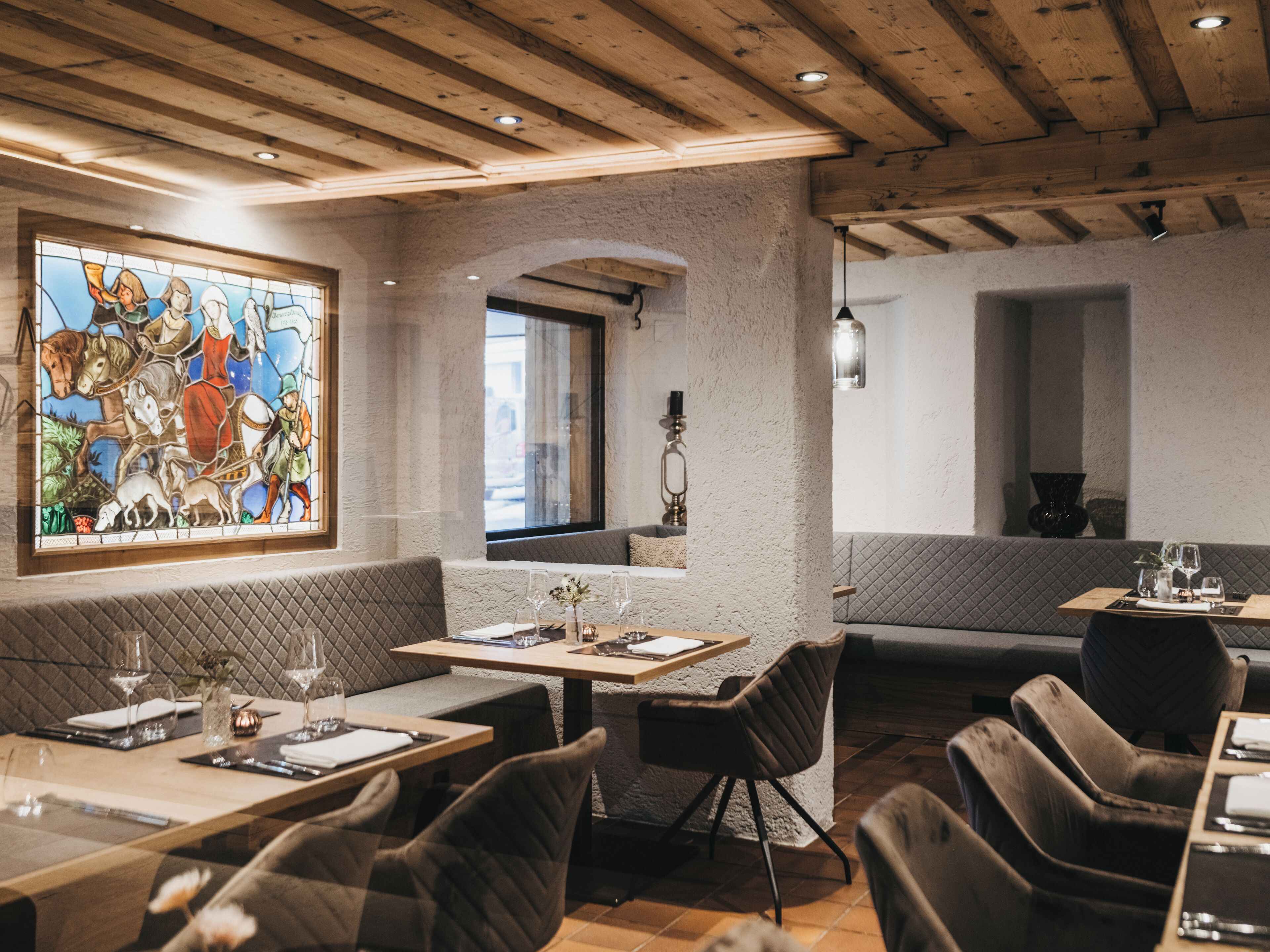 Un restaurante con vigas de madera, vidrieras y asientos acolchados.