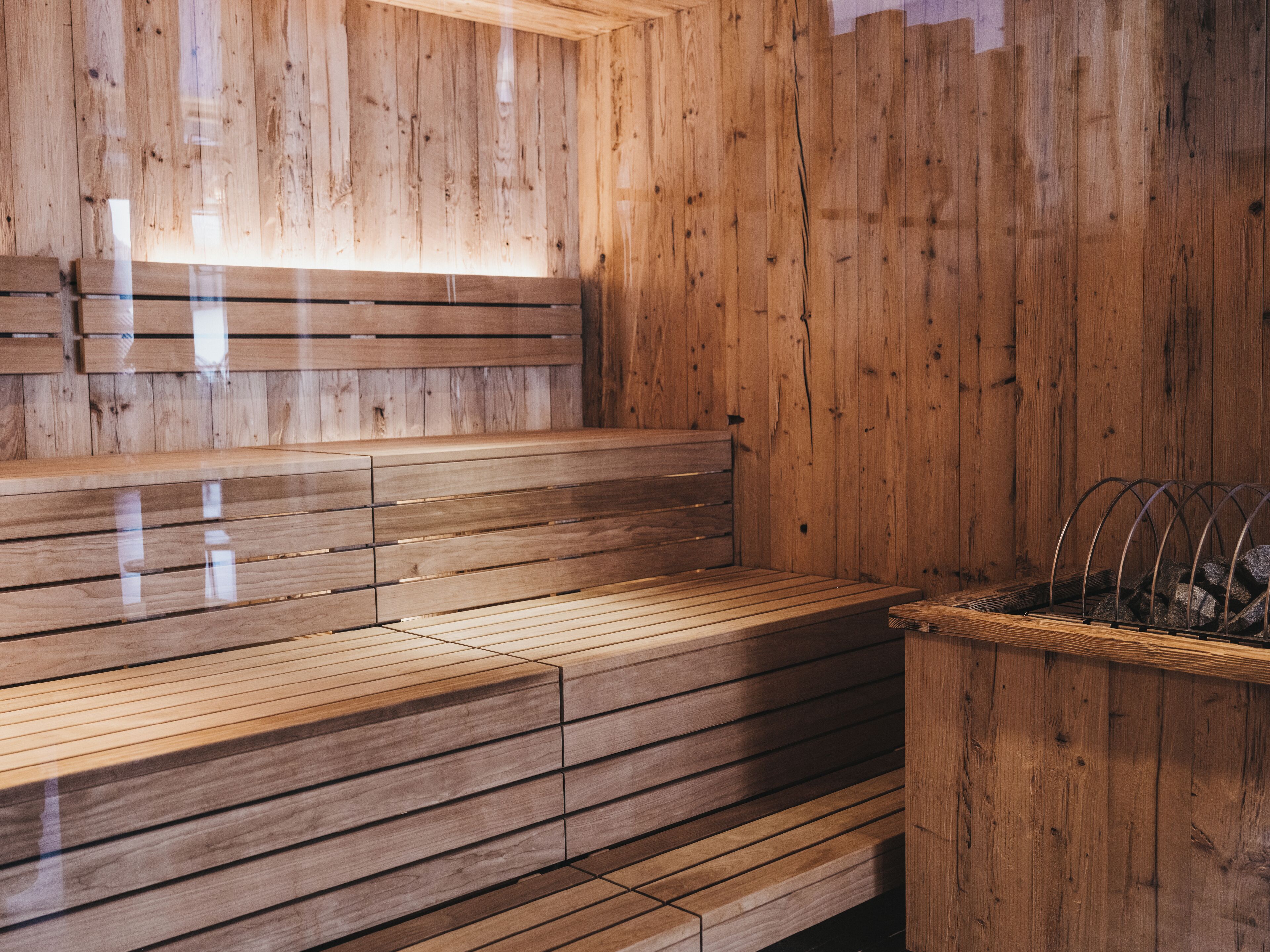 Una sauna de madera con bancos y un recipiente de piedra.