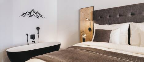 Un dormitorio con cama, una lámpara fijada a la pared, un panel de madera y un adhesivo mural de montañas.