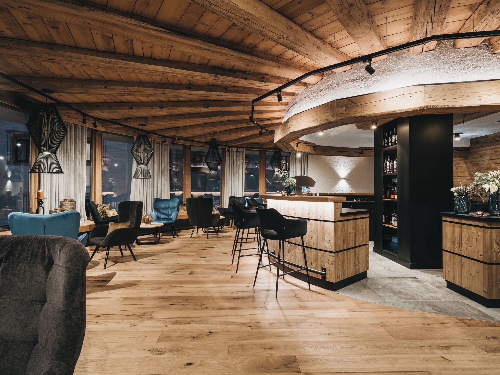 Un intérieur moderne avec un plafond en bois, un espace bar, des sièges et de grandes fenêtres.