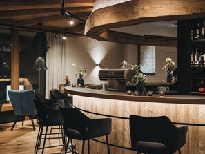 A bar area with wooden furniture, a piano, and a selection of bottles. - VAYA Nauders (Nauders)