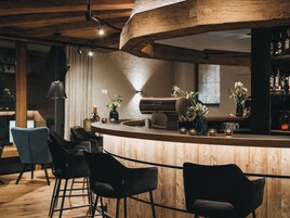 Zona de bar con mobiliario de madera, un piano y una variedad de botellas.