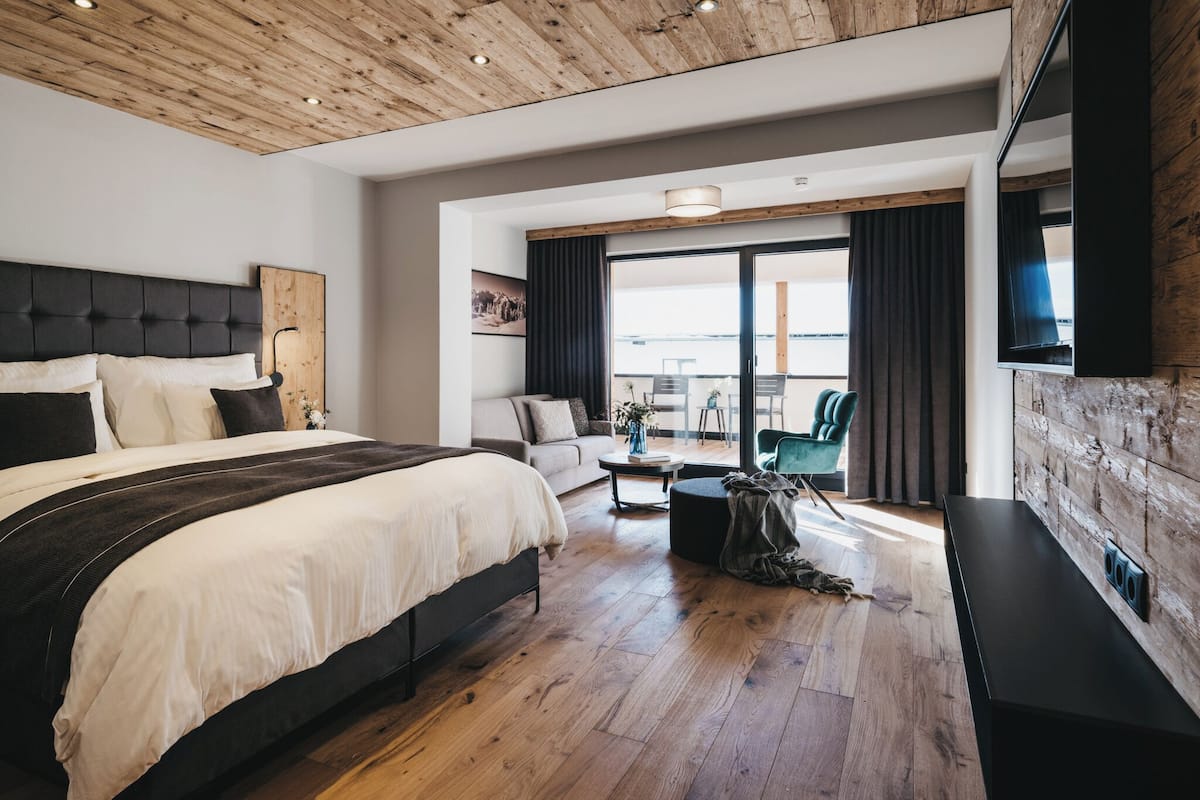 Un dormitorio moderno con una cama grande, un sofá, un televisor y un balcón con vistas.