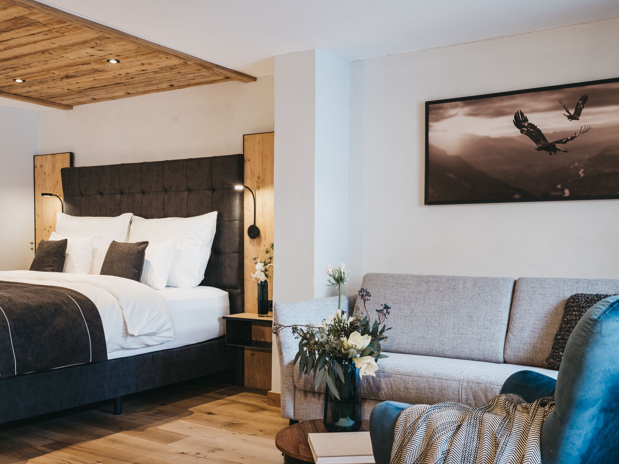 Ein modernes Schlafzimmer mit einem großen Bett, einer Couch und einem Vogelgemälde.