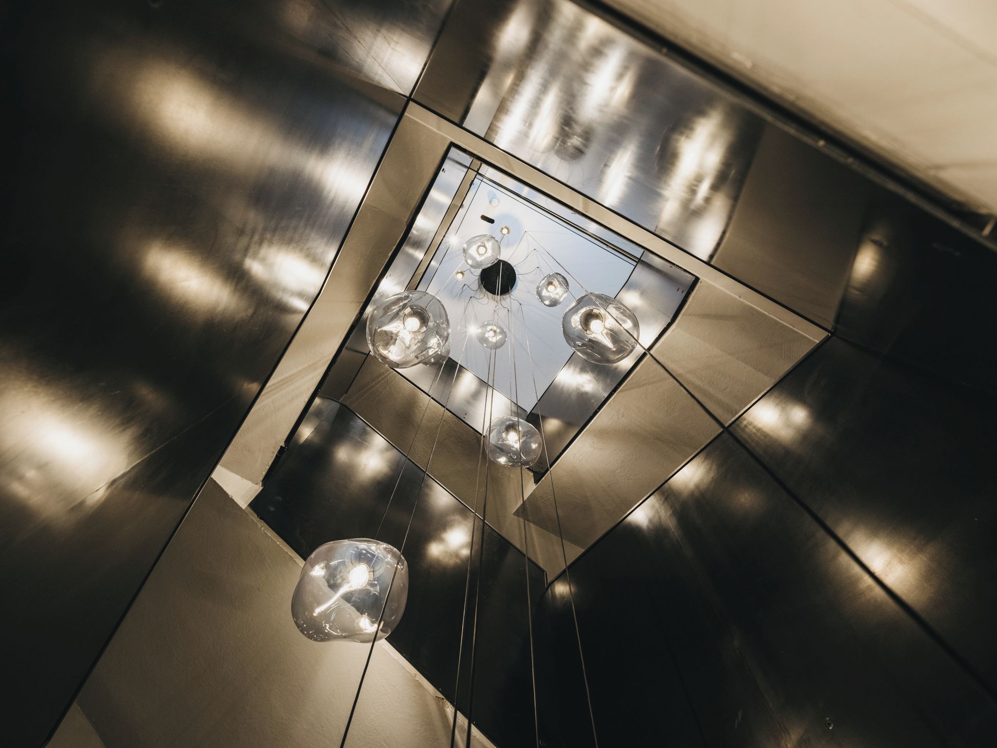 Un pavimento metallico con una bocchetta quadrata e quattro luci sferiche.
