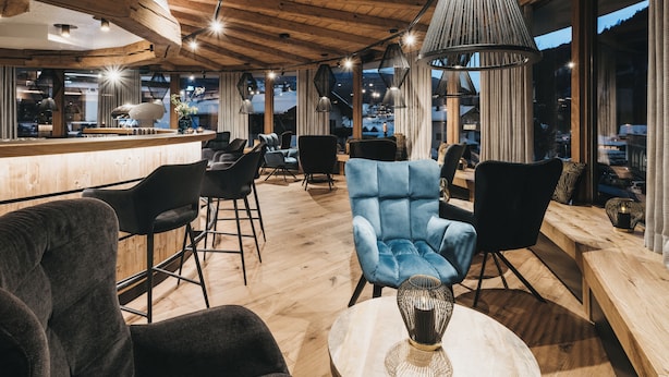 Un rincón de sala acogedor con suelo de madera, mobiliario moderno y ventanas amplias que ofrecen vistas al exterior.