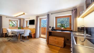 Eine moderne Küche mit Holzarbeitsplatte, integriertem Spülbecken und Blick auf eine gebirgige Landschaft durch große Fenster.