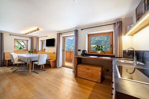 Une cuisine moderne dotée d’un plan de travail en bois, d’un évier encastré et offrant une vue sur un paysage montagneux grâce à de grandes fenêtres.