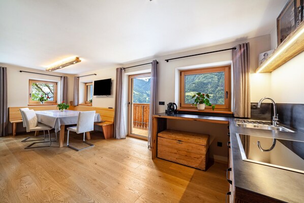 A modern kitchen with a wooden countertop, a built-in sink, and a view of a mountainous landscape through large windows.