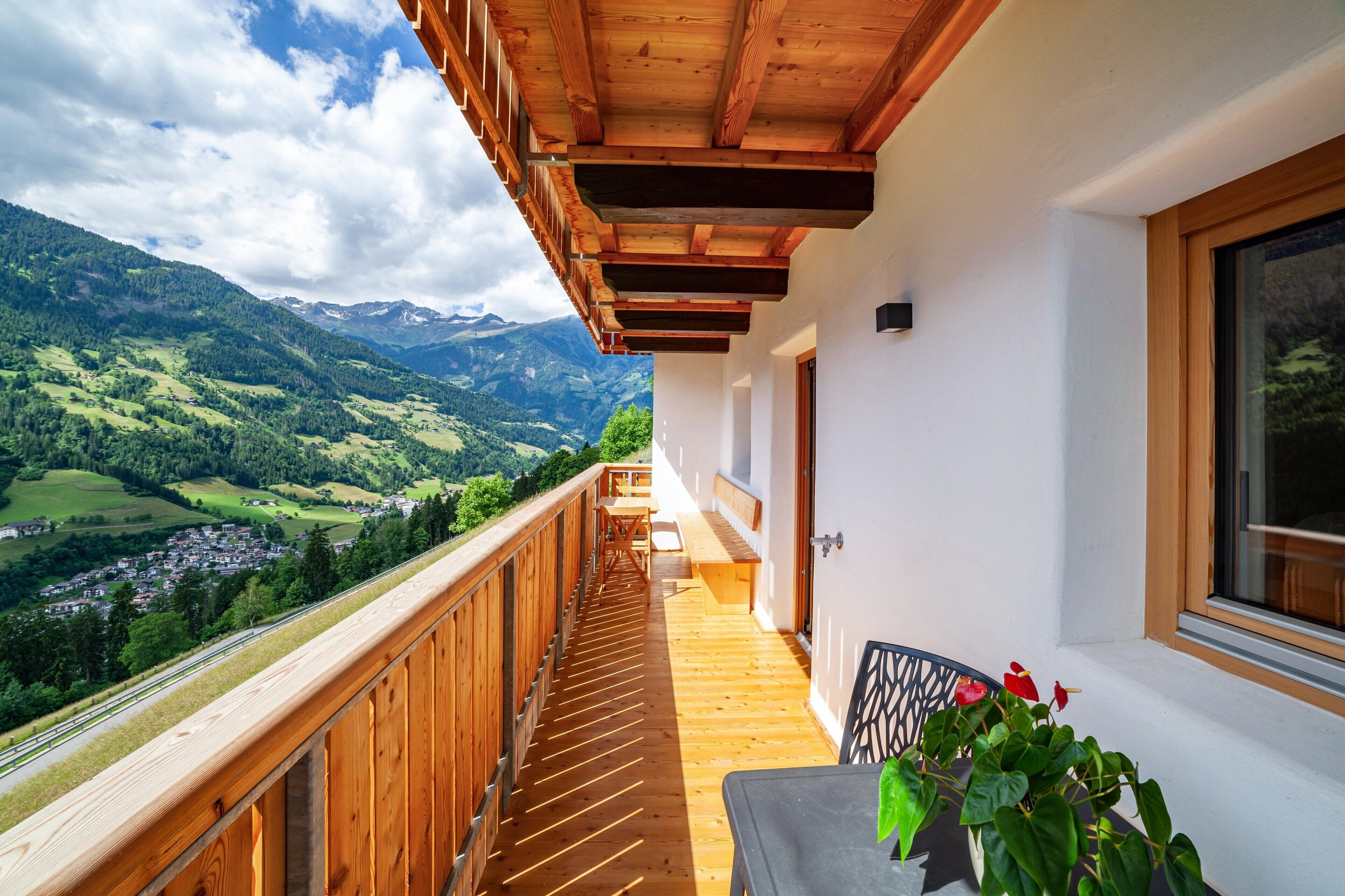 Ein Balkon mit Holzgeländer, einem Tisch und einem Blumentopf.